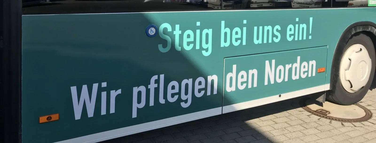 Türkisfarbene Busseite mit der Hansepflege-Werbung: „Steig bei uns ein! Wir pflegen den Norden“